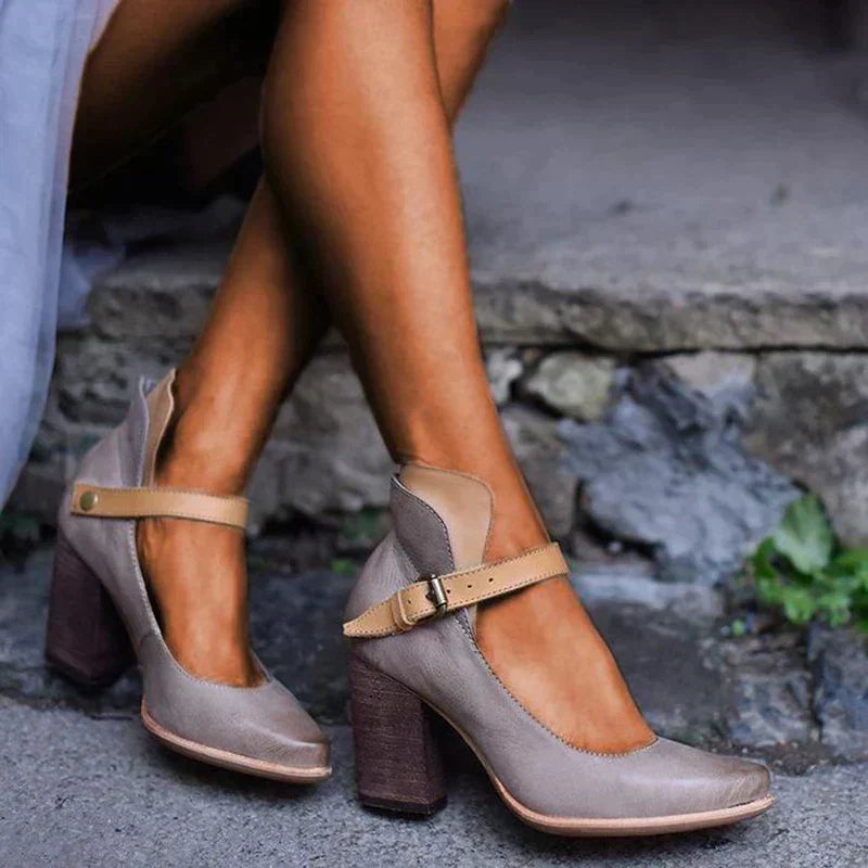 Woman showcasing stylish open toe heel sandals on a plain background.