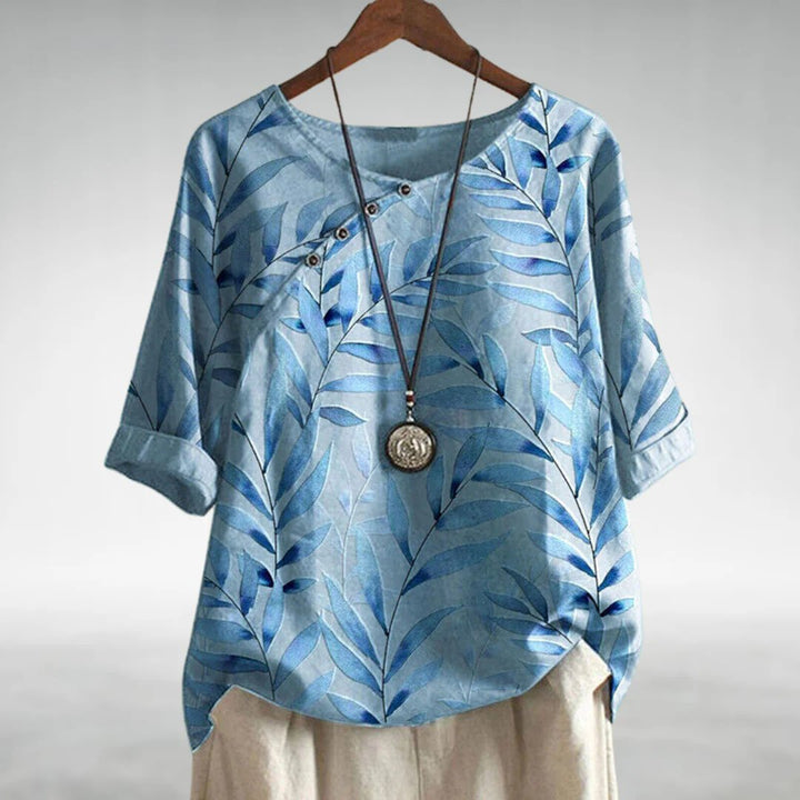 Woman wearing a lightweight blouse with an asymmetric button front against a plain background.