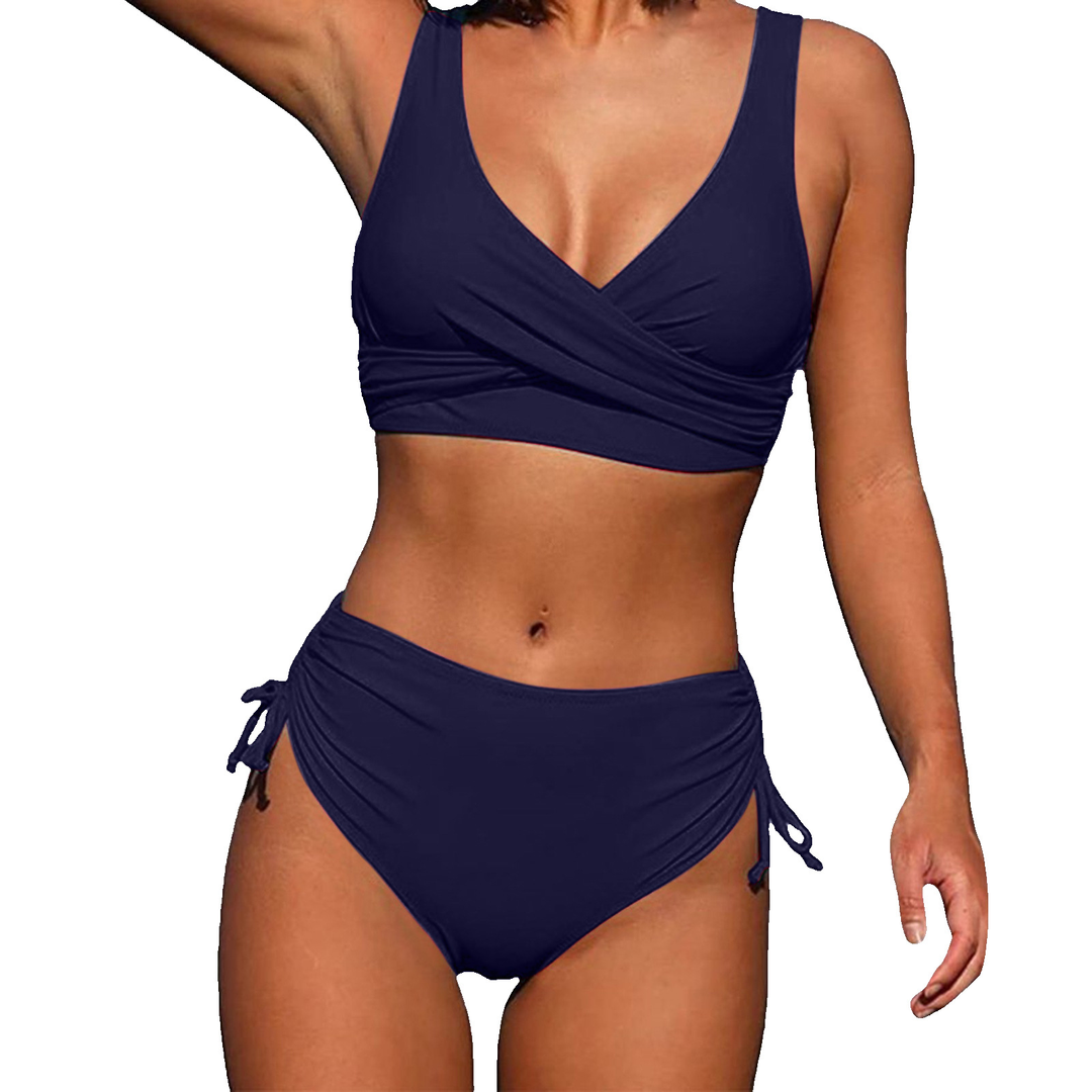 Woman in a vacation ready high waisted swimsuit on a plain background.