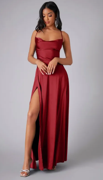Female model wearing a long formal dress with side slit and plain background.