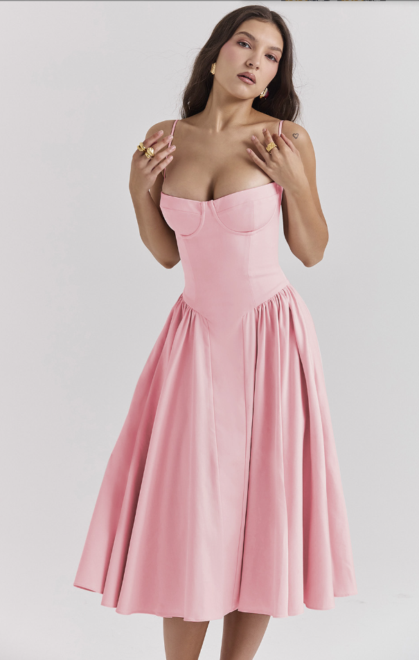 Female model in a summer dress with narrow straps on a plain background.