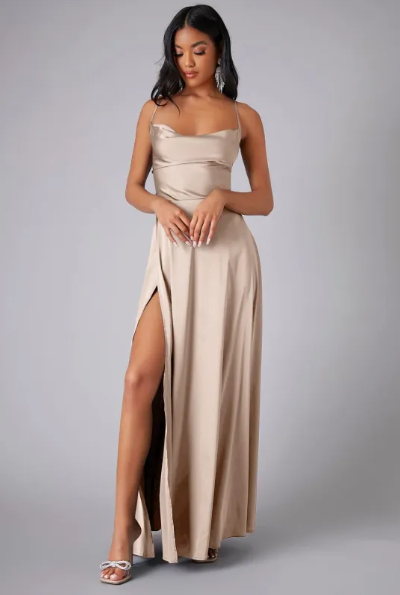 Female model in a formal maxi dress with draped neckline and flowing skirt.