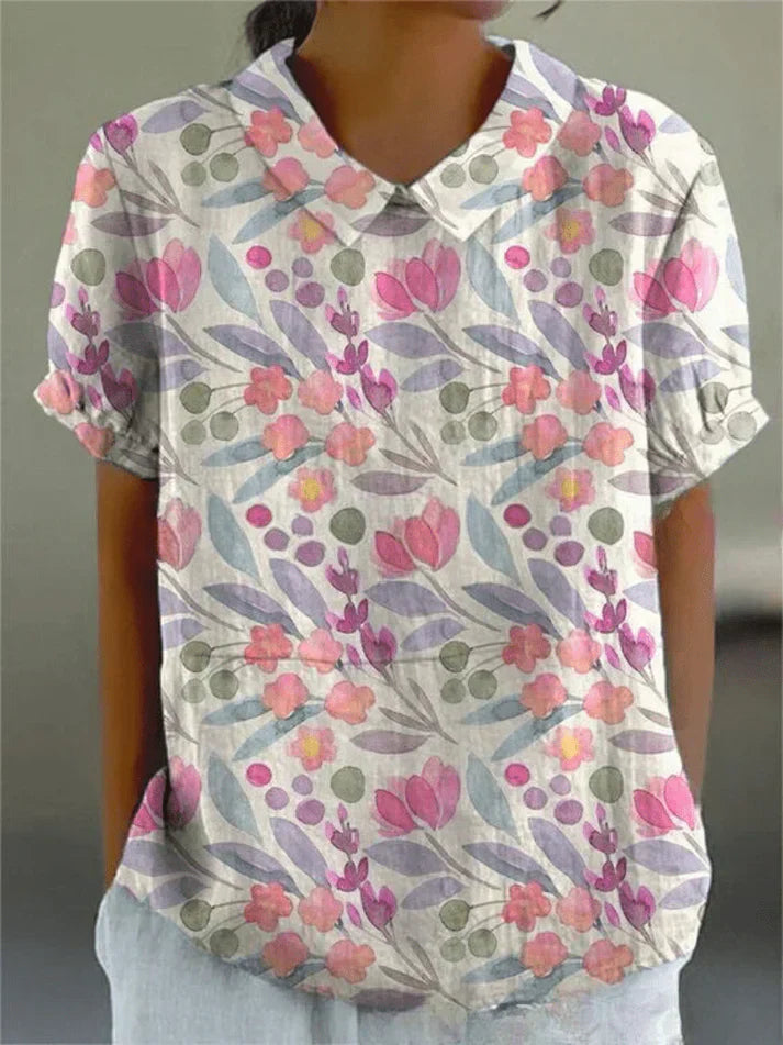 Woman wearing a floral print blouse with a structured collar on a plain background.