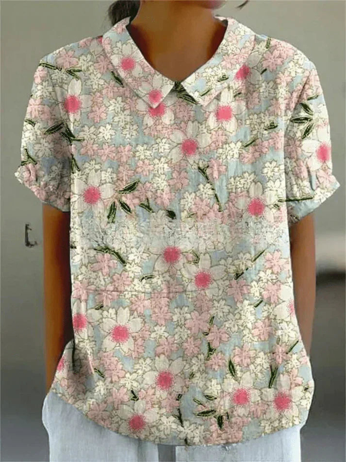 Female model wearing a floral blouse with an easy relaxed shape on a plain background.