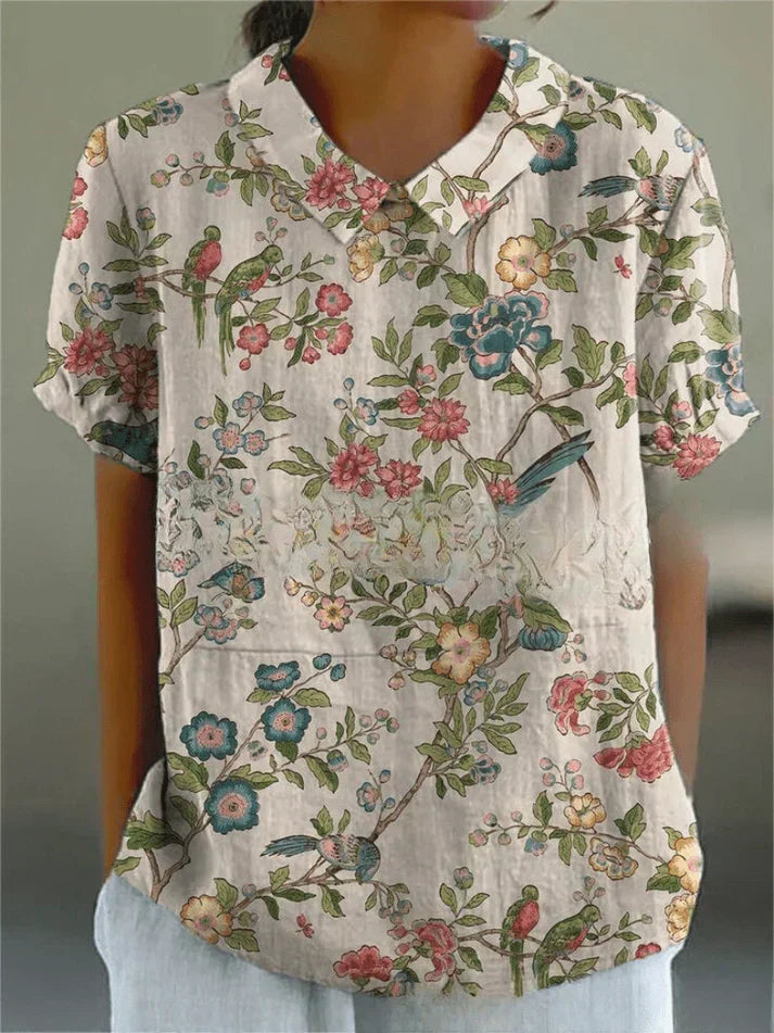 Female model styled in a floral blouse for casual wear on a plain background.