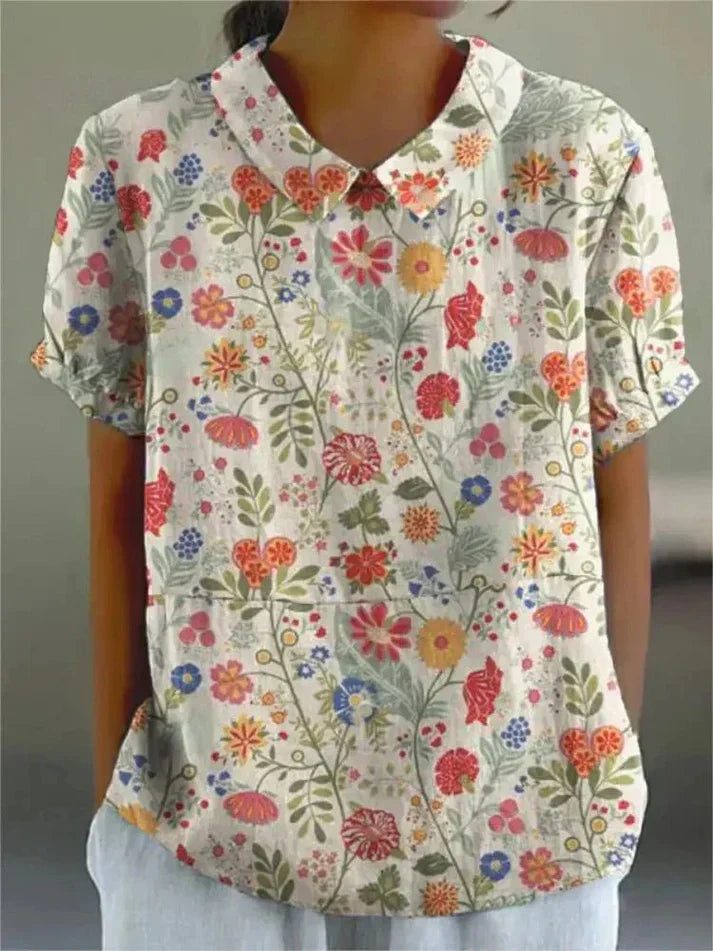 Model wearing a relaxed floral blouse with long sleeves on a plain background.