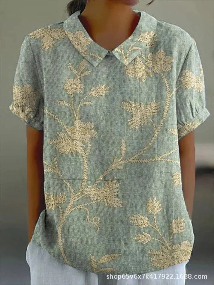 Model showcasing a floral blouse with a polished collar on a plain background.