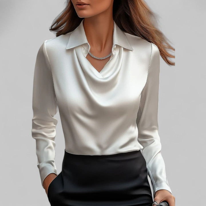 Female model wearing a long sleeve satin blouse with a draped neckline against a plain background.