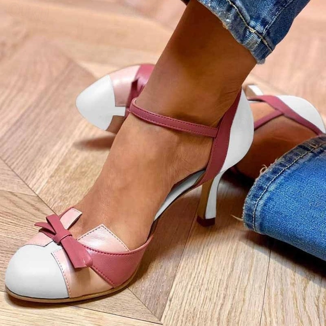Female model showcasing slim heel sandals with an ankle strap on a plain background.