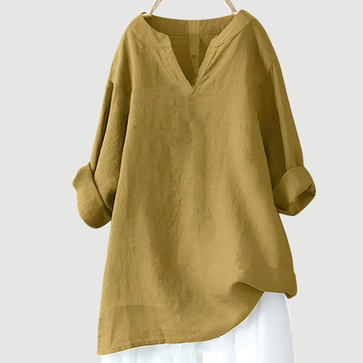 Female model wearing a breezy oversized shirt on a plain background.