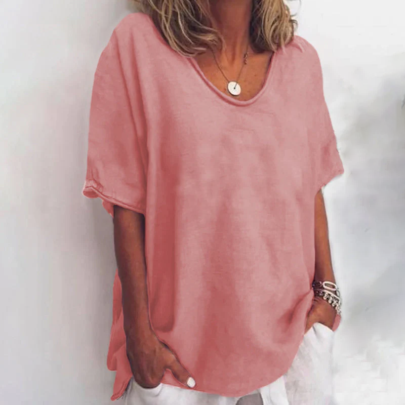 Woman wearing a loose-fit blouse with a relaxed draped silhouette against a plain background.