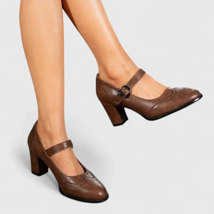 Woman wearing brown Mary Jane block heel shoes on a plain background.