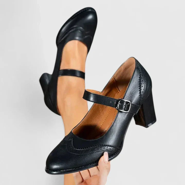 Woman showcasing classic Mary Jane block heels on a plain background.