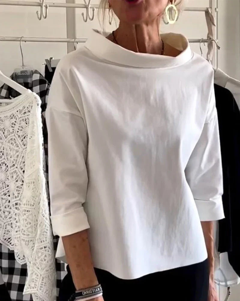 Woman wearing a bateau neck top with 3/4 sleeves against a plain background.