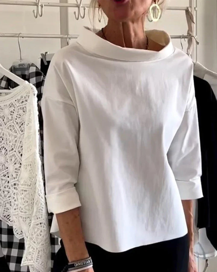 Woman wearing a bateau neck top with 3/4 sleeves against a plain background.