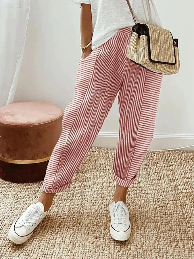 Woman showcasing vertical striped trousers styled for everyday wear on a plain background.