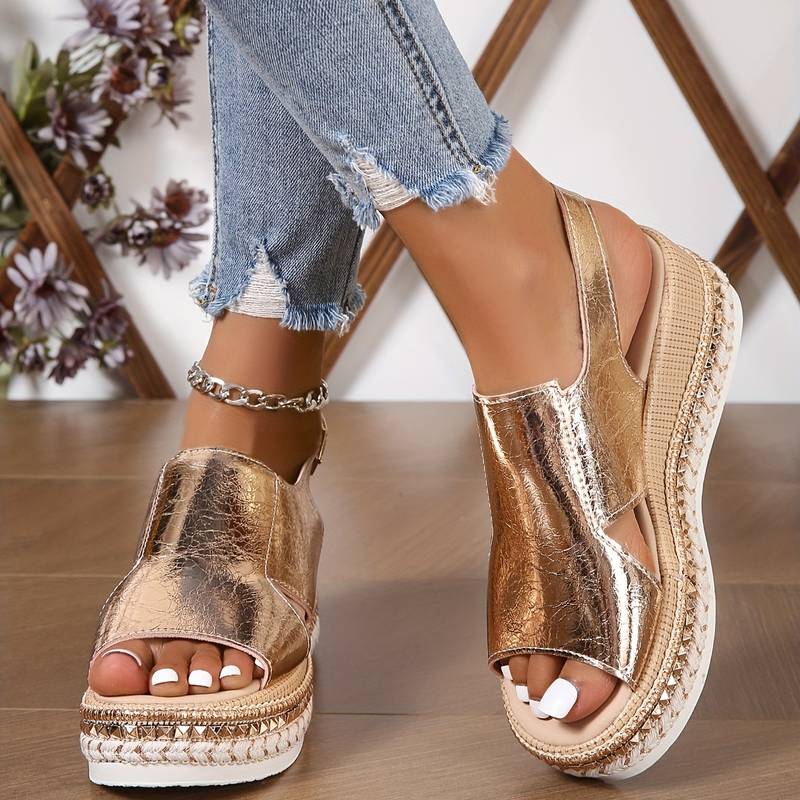  Woman wearing lightweight summer sandals with a star design on a plain background.