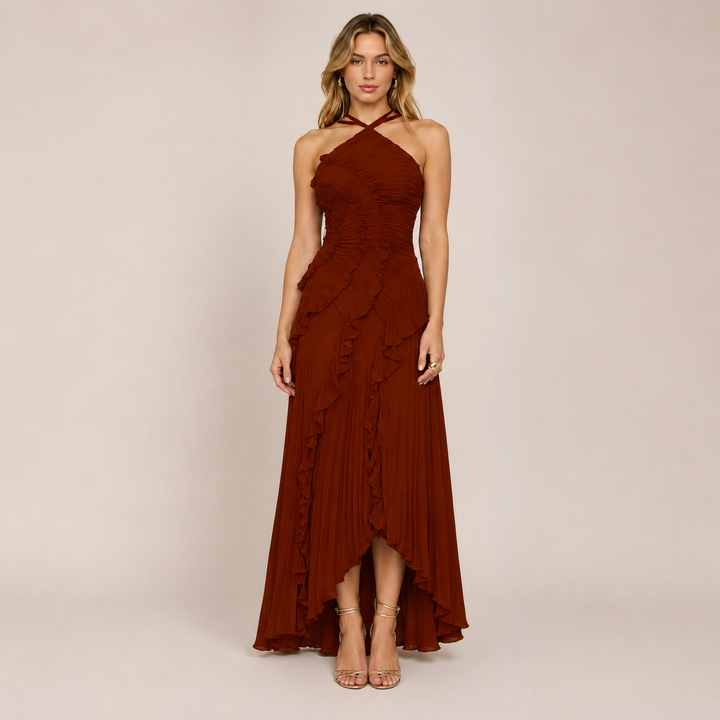 Woman wearing a graceful halter dress with soft movement on a plain background.