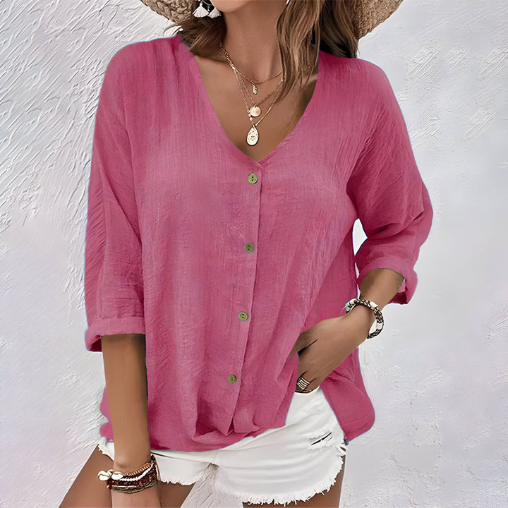 Female model showcasing a button-front blouse with a relaxed silhouette against a plain backdrop.