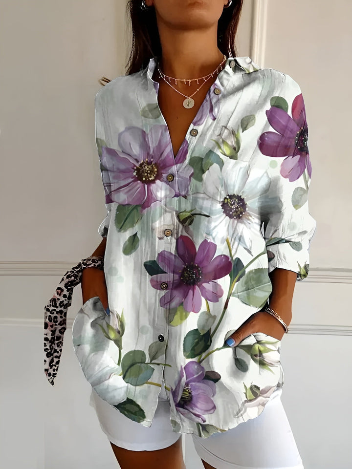 Woman in a button-front floral blouse with airy short sleeves on a plain background.