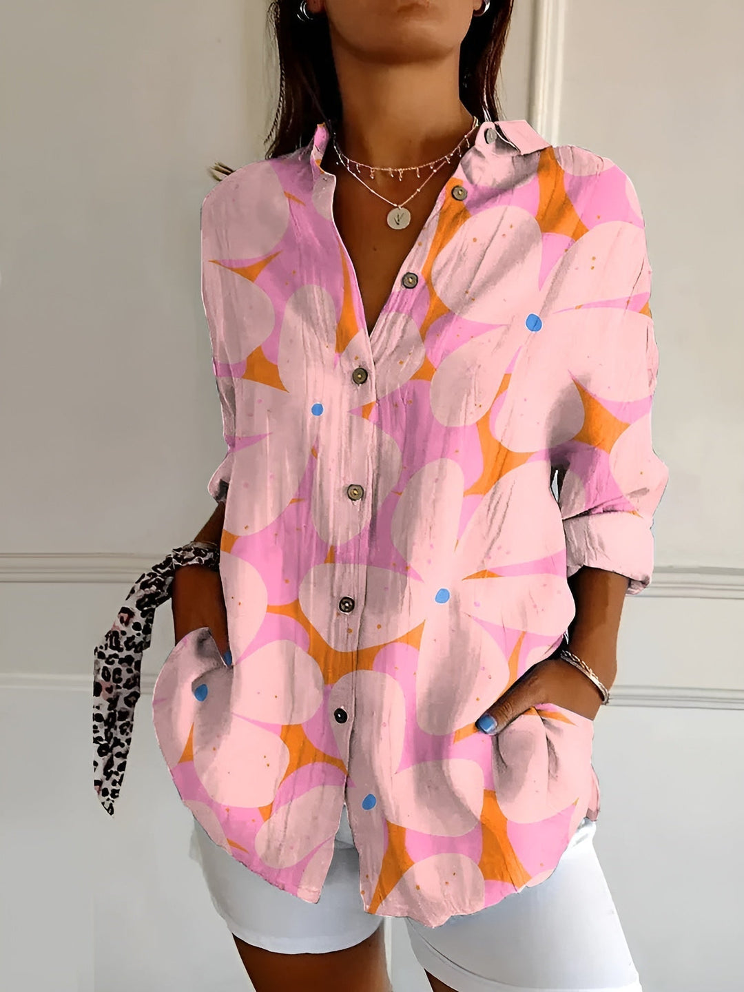 Woman modeling a colorful floral shirt with an easy silhouette on a plain background.