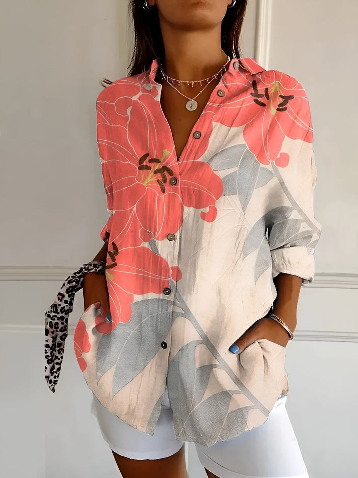 Female wearing a bright floral blouse paired with a relaxed summer style on a plain background.