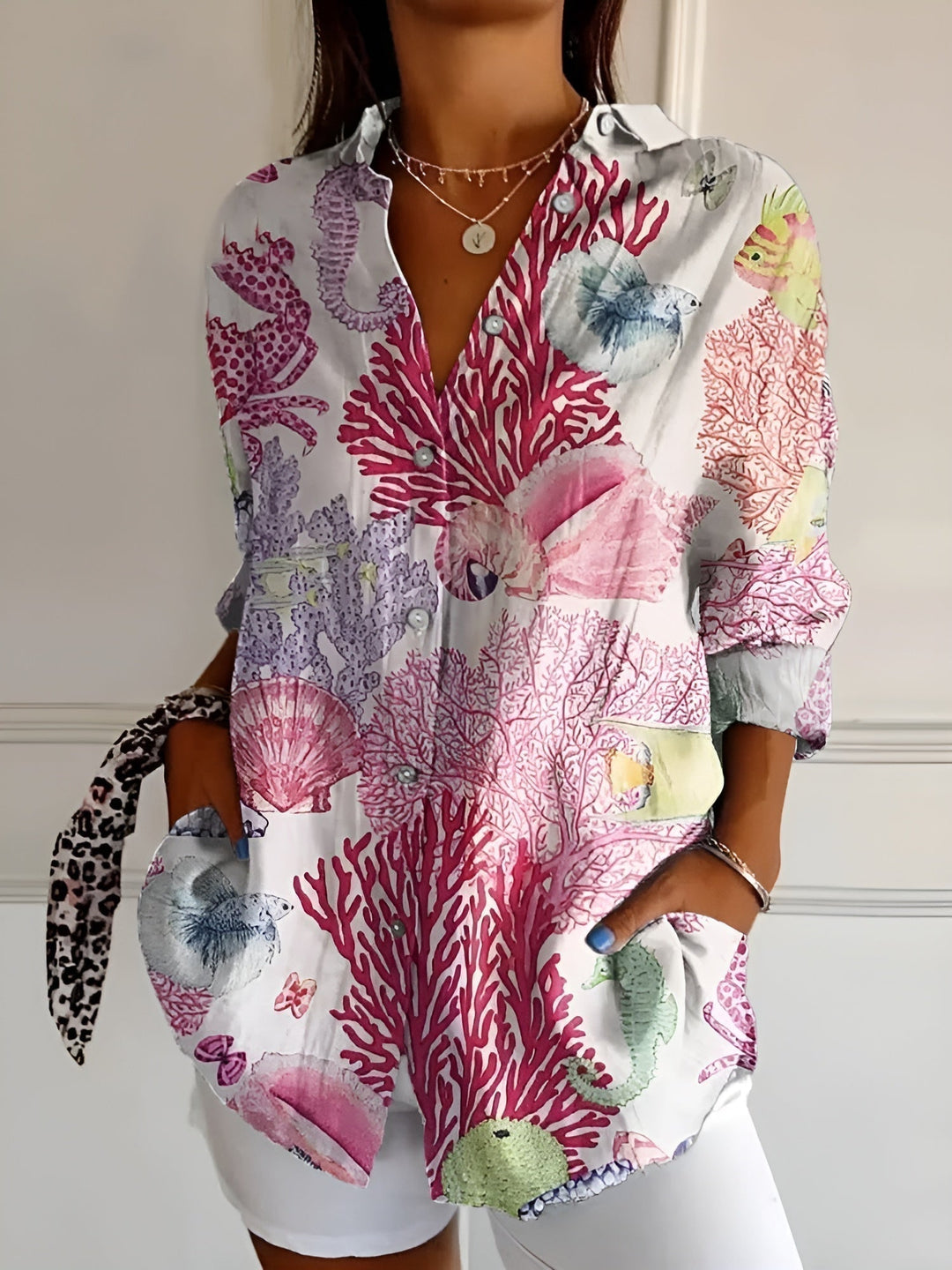 Woman wearing a relaxed fit floral top with button-front detail on a plain background.