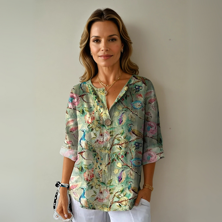  Woman in a long sleeve floral blouse on a plain background.