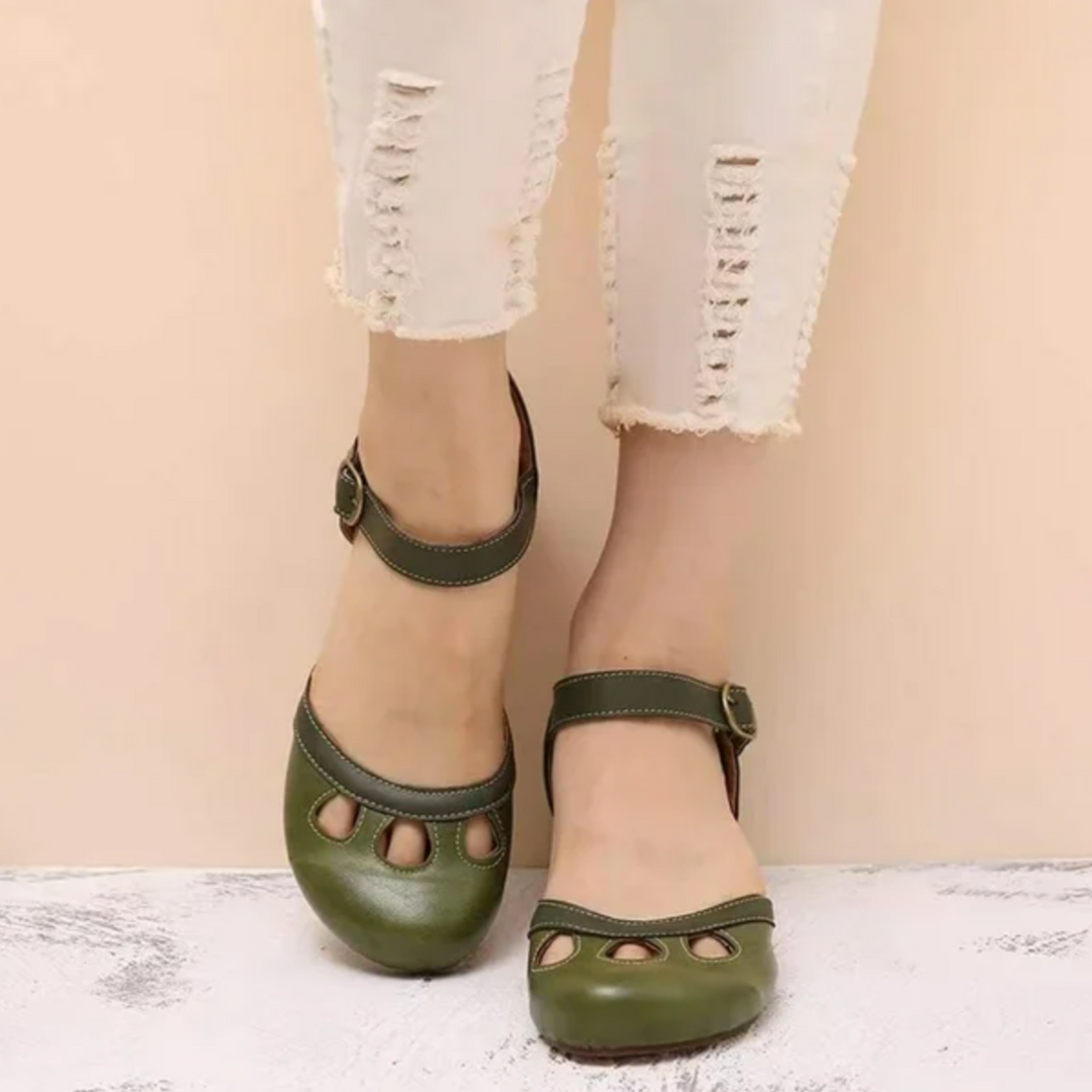 Woman wearing low heel sandals against a plain background.
