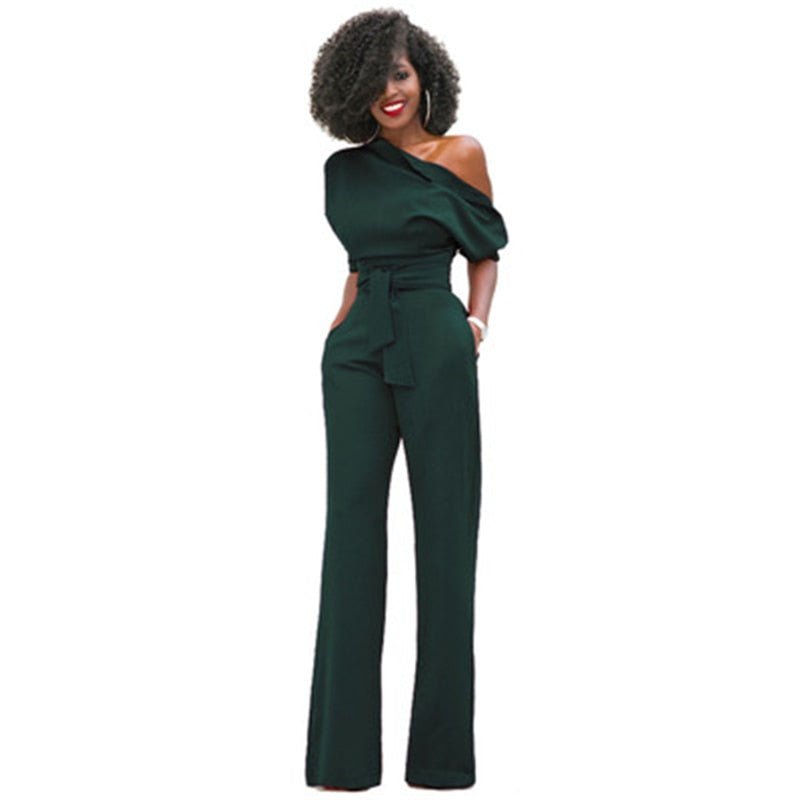 Woman in a bold one-shoulder jumpsuit with a defined waist on a plain background.
