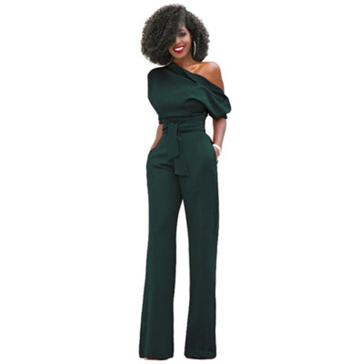Woman in a bold one-shoulder jumpsuit with a defined waist on a plain background.