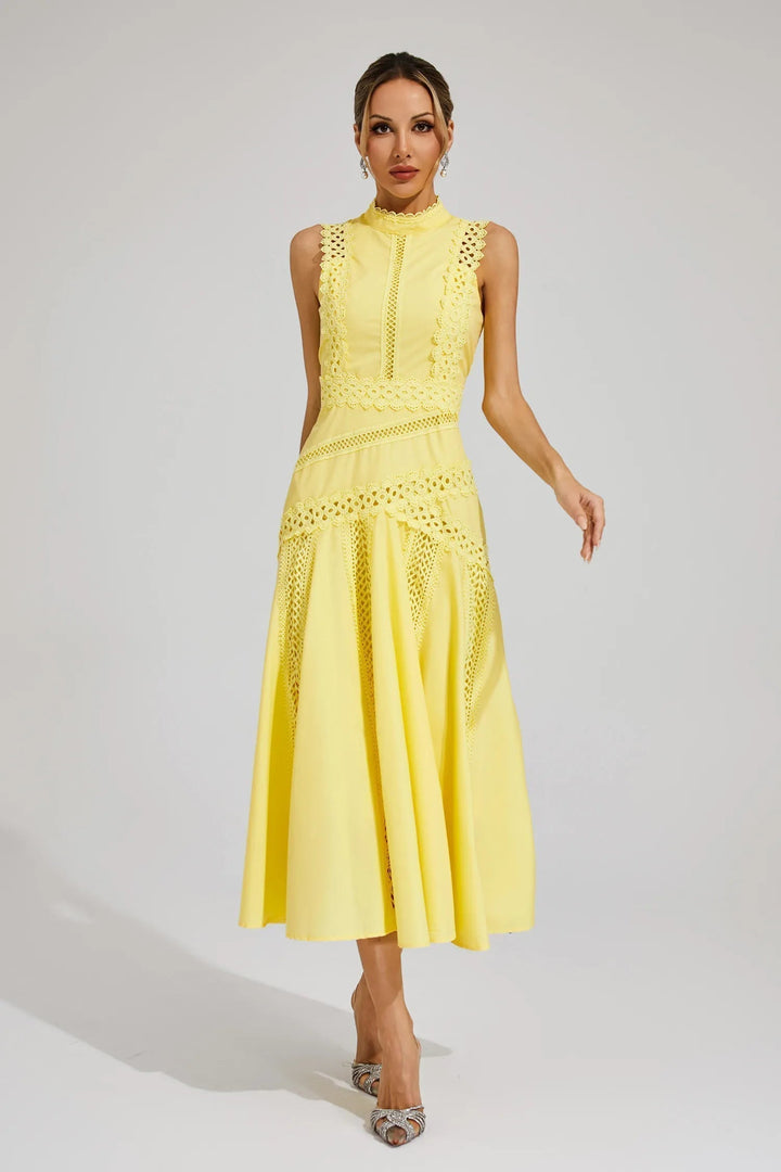 Woman wearing a sleeveless midi dress with decorative detailing on a plain background.