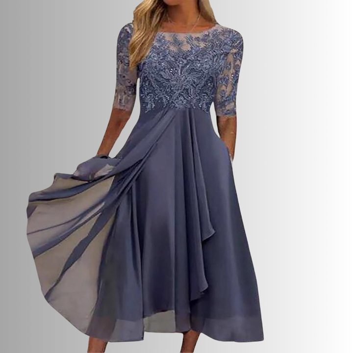 Woman in an embroidered midi dress with A-line shape and practical pockets against a plain background.