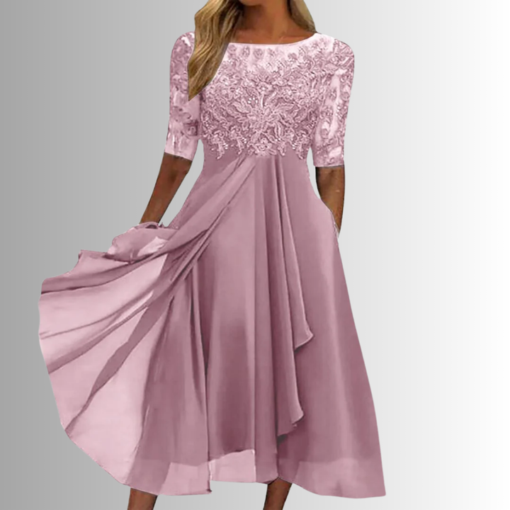Female model in a lace-embroidered bodice midi dress with a flowing skirt on a plain background.