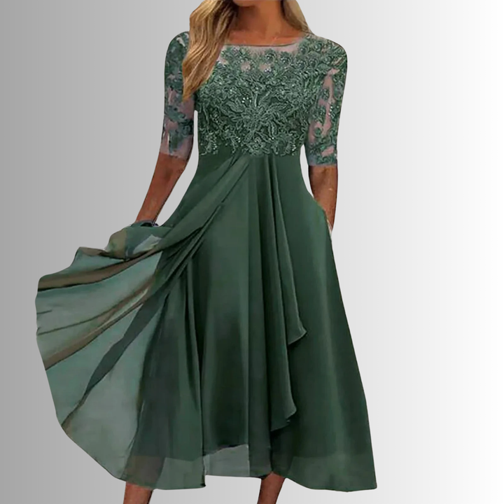 Female model wearing a midi dress with textured bodice detail and soft skirt flow on a plain background.
