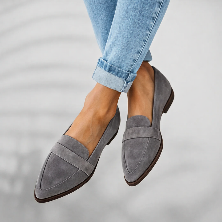 Woman standing in sleek pointed toe loafers against a plain background.