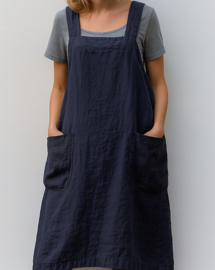 Woman modelling a relaxed sleeveless midi dress with an apron-inspired shape.