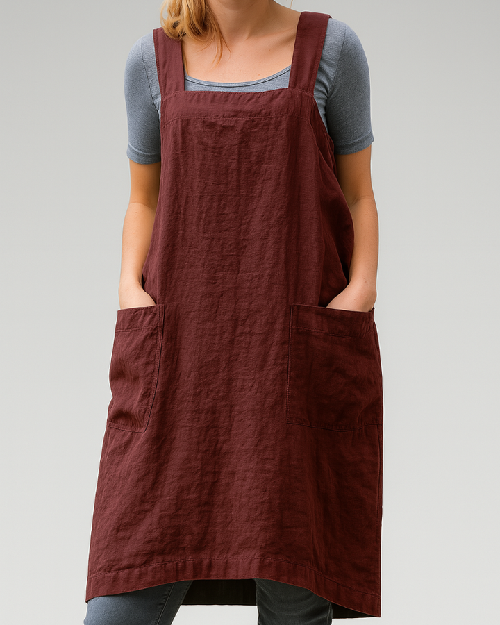 Woman wearing a sleeveless apron-style midi dress against a plain background.