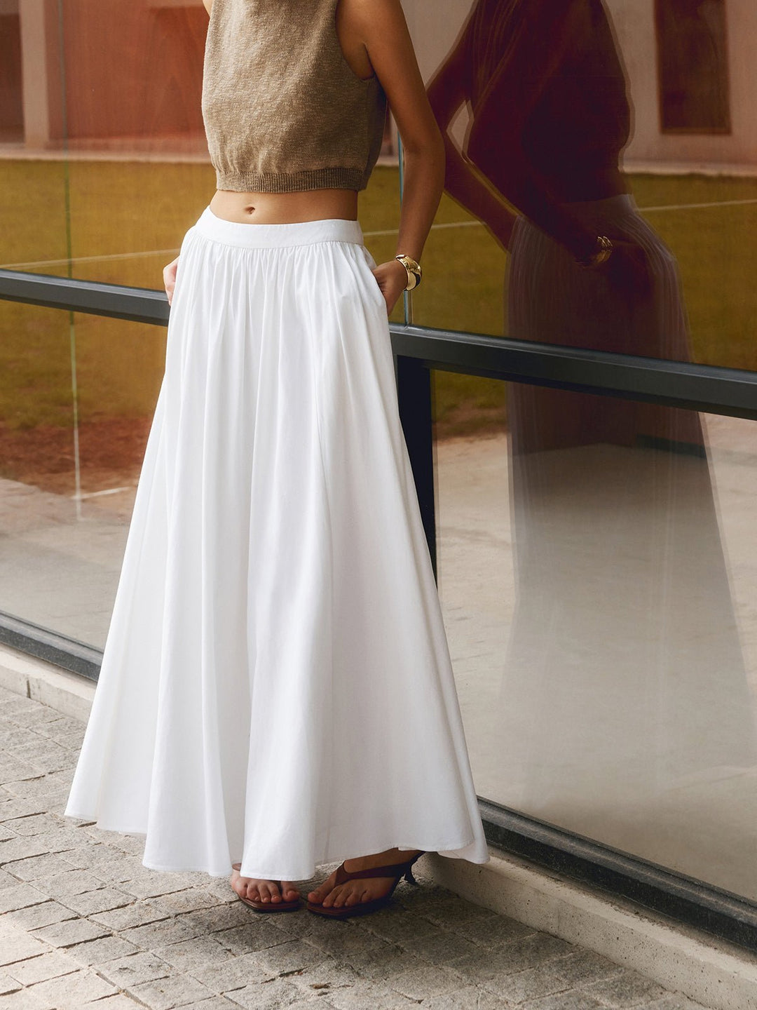 Female model wearing a long pleated maxi skirt with a high waist on a plain background.