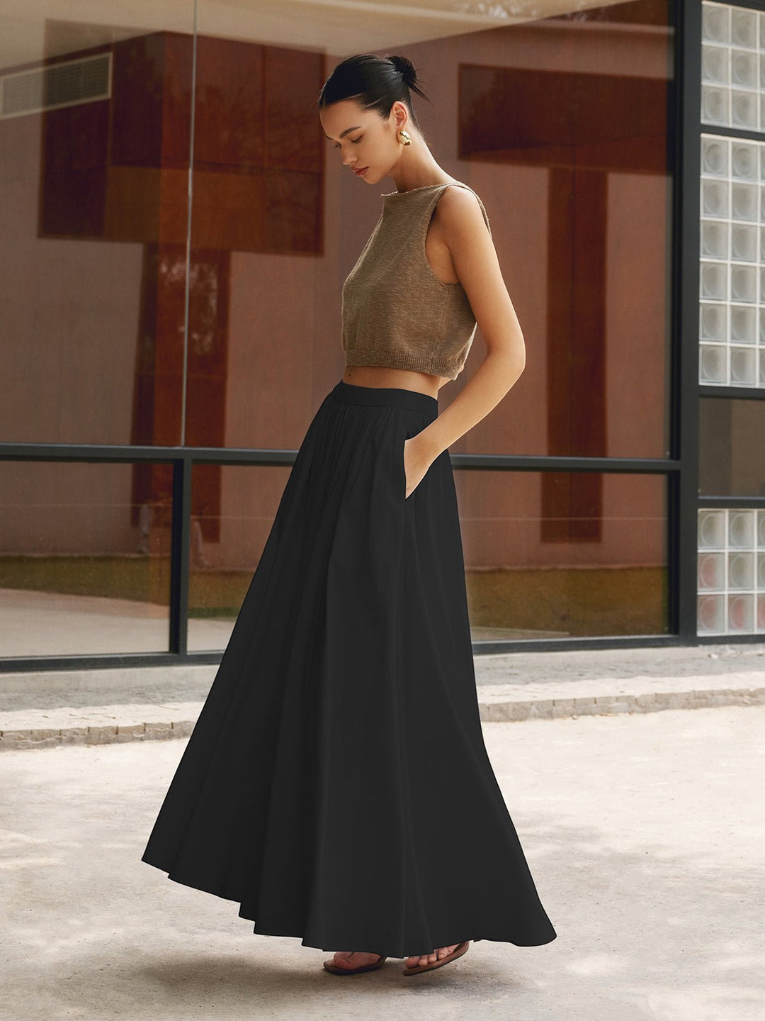 Female model wearing a flowing maxi skirt with side pockets on a plain background.