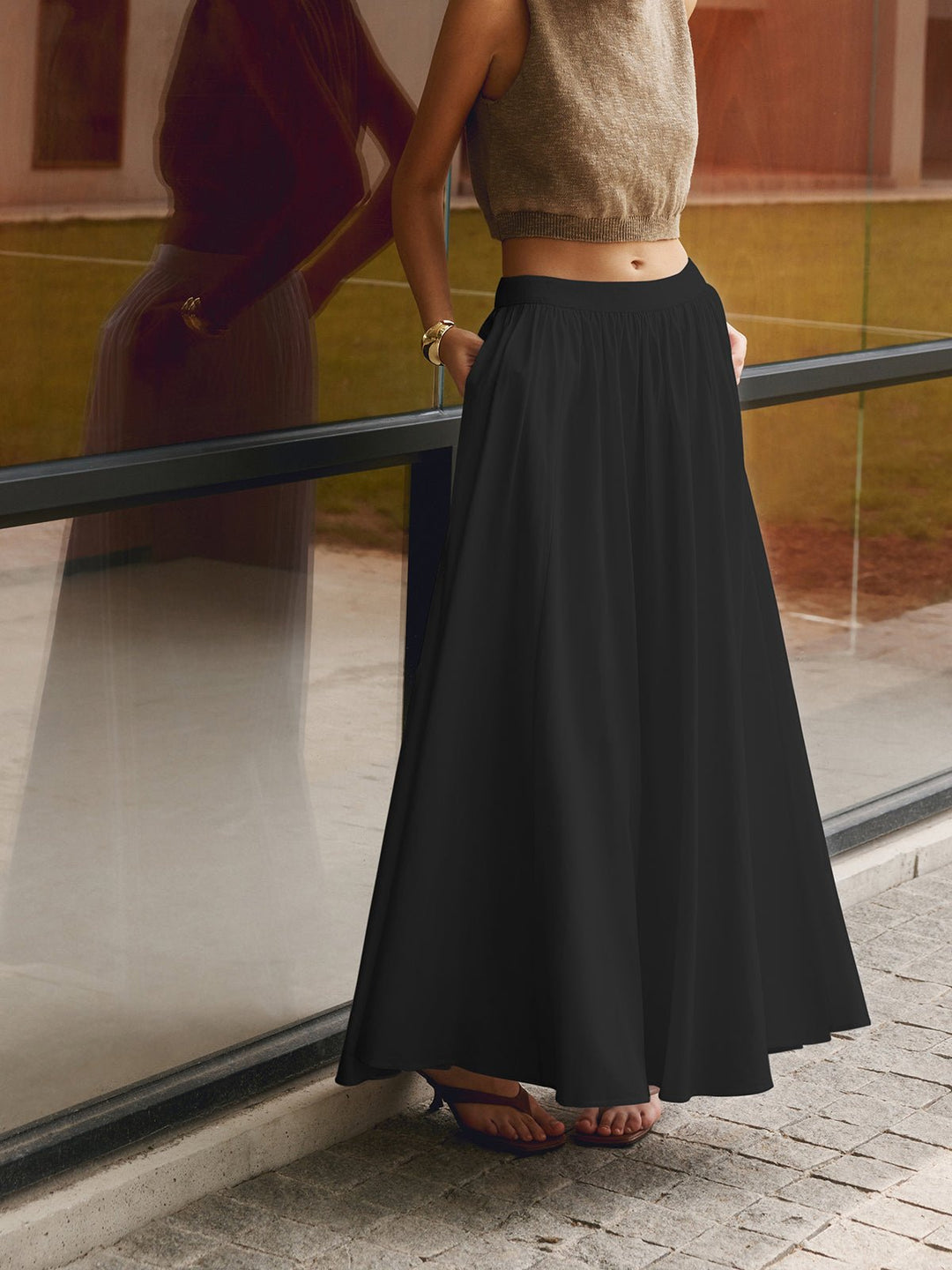 Woman in a high waist pleated skirt shown from the front on a plain background.