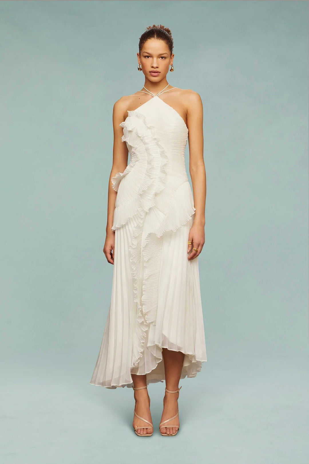  Woman showcasing a flowing maxi dress with an asymmetrical neckline on a plain background.