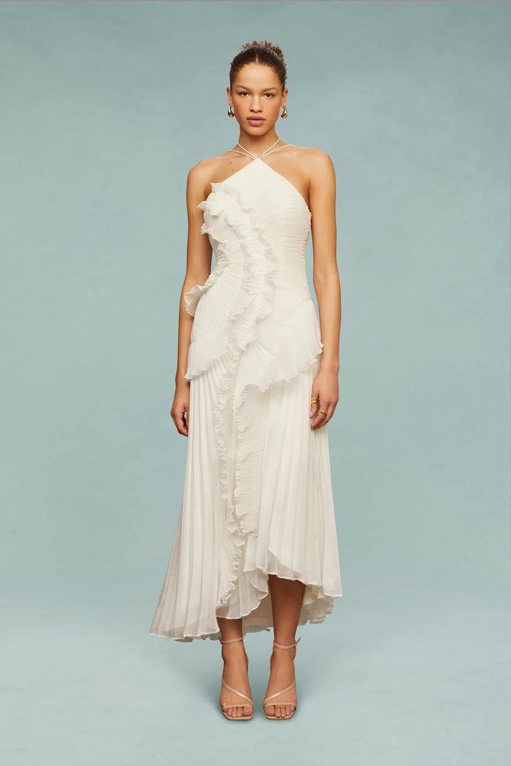  Woman showcasing a flowing maxi dress with an asymmetrical neckline on a plain background.