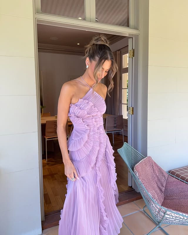  Woman wearing a maxi dress with a structured bodice and flowing skirt on a plain background.