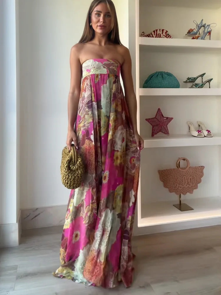 Female wearing a strapless floral maxi dress with a flowing silhouette on a plain background..