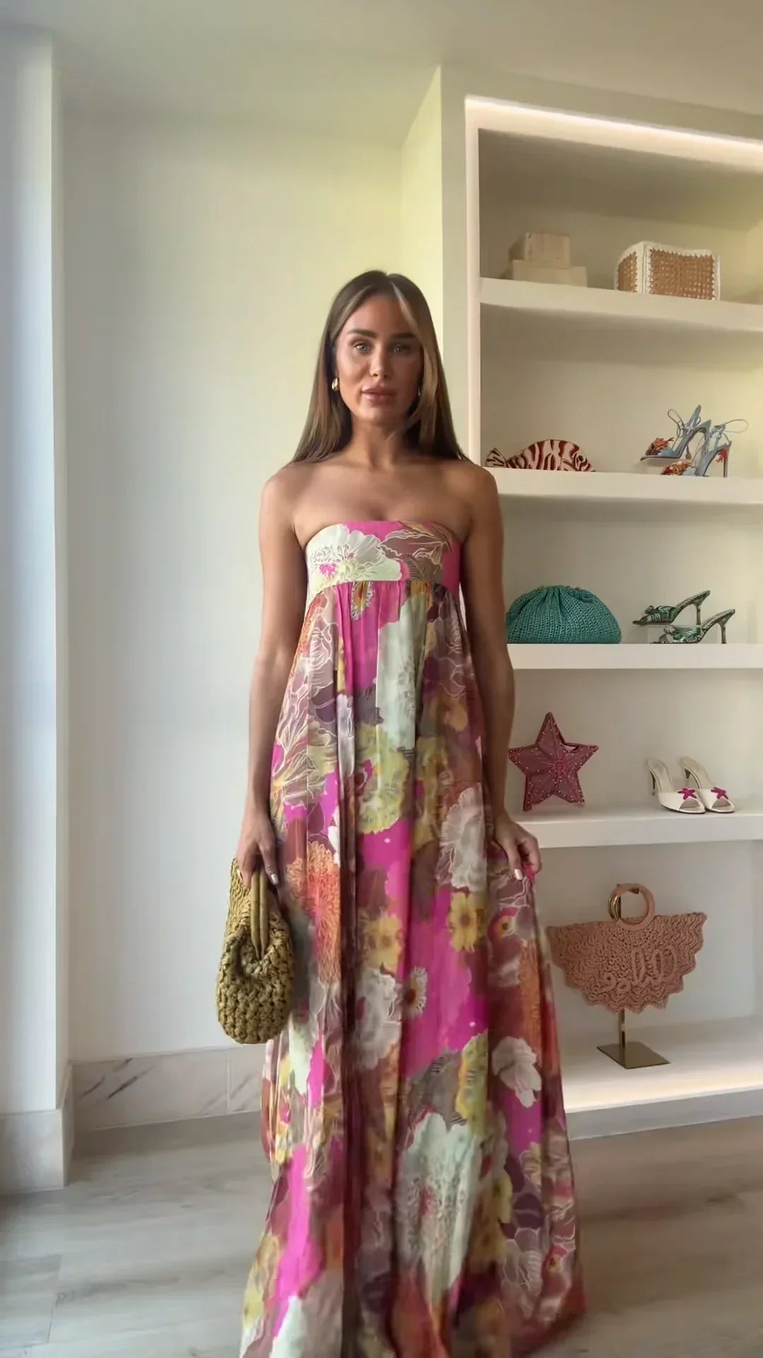  Woman wearing a flowing maxi dress with floral detailing on a plain background.