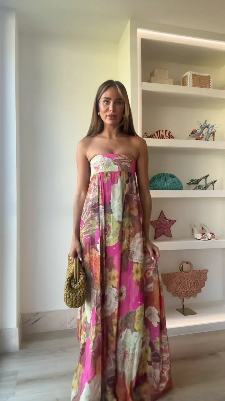  Woman wearing a flowing maxi dress with floral detailing on a plain background.