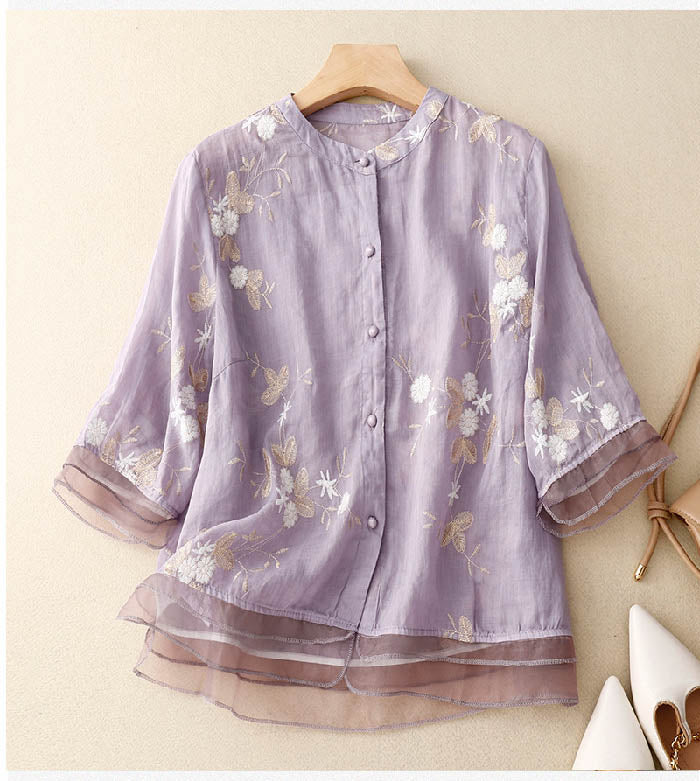 A relaxed fit embroidered blouse on a plain background.X