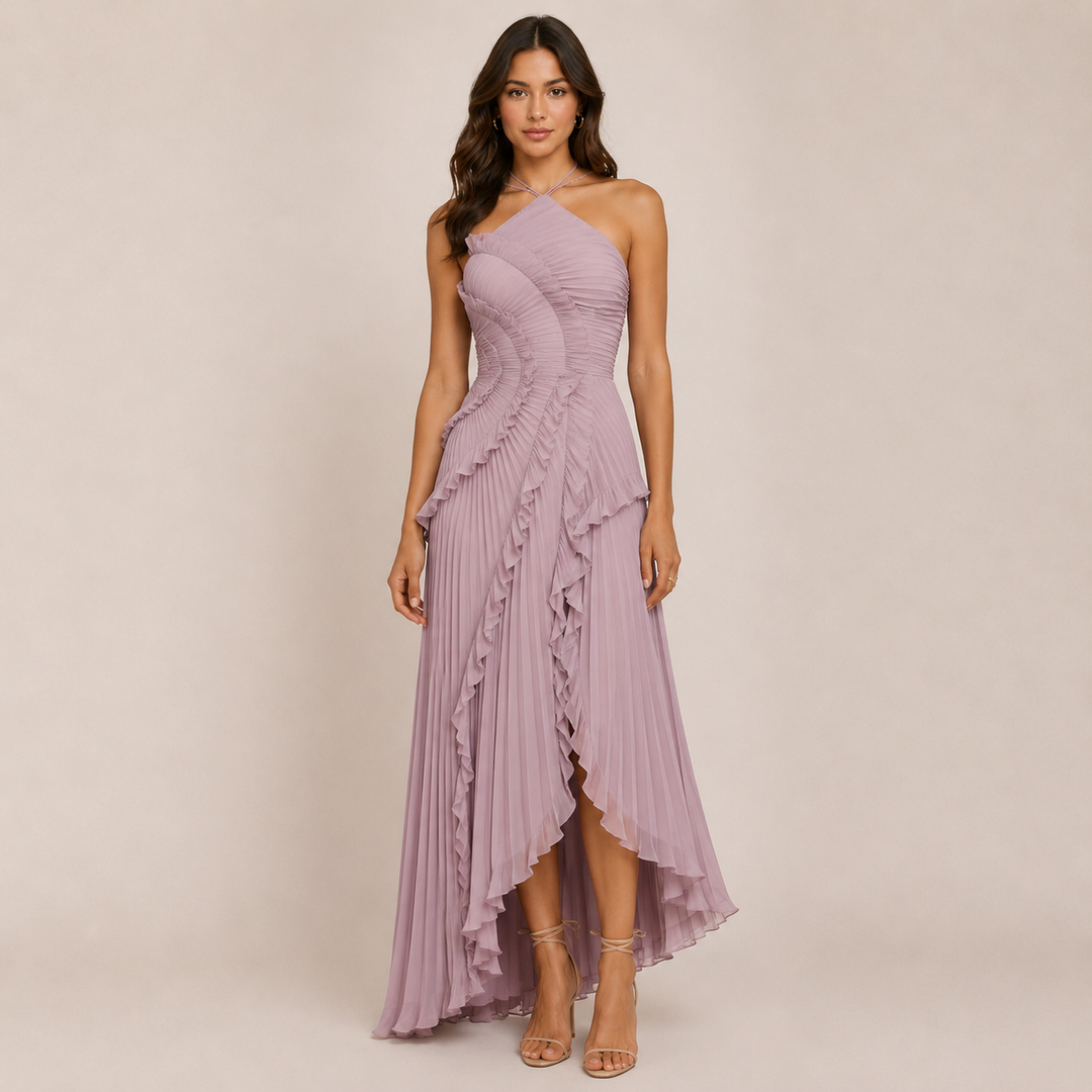 Woman posing in a sleeveless halter dress with a flowing skirt on a plain background.