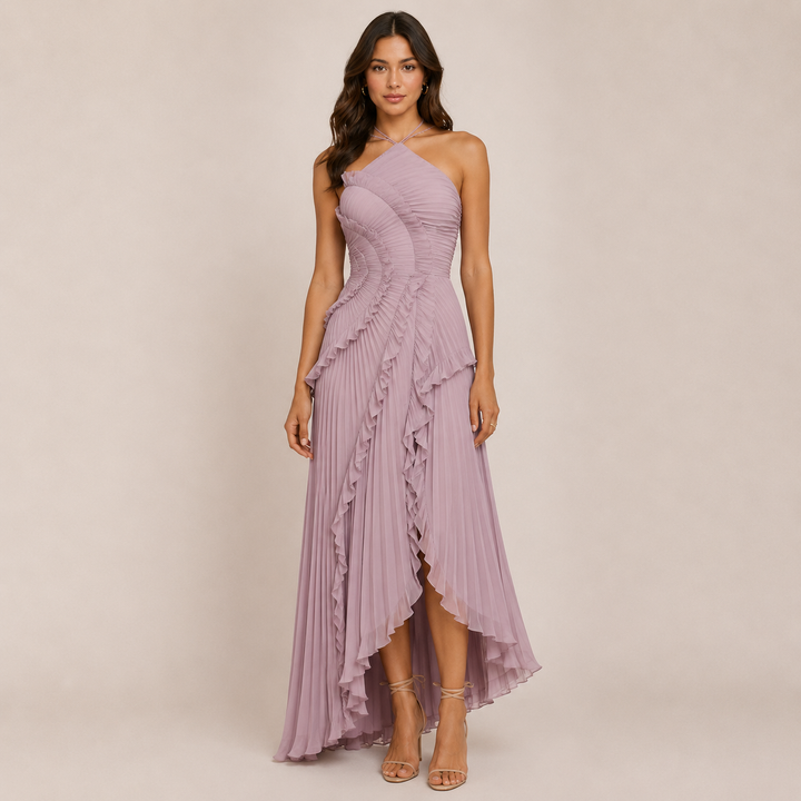Woman posing in a sleeveless halter dress with a flowing skirt on a plain background.